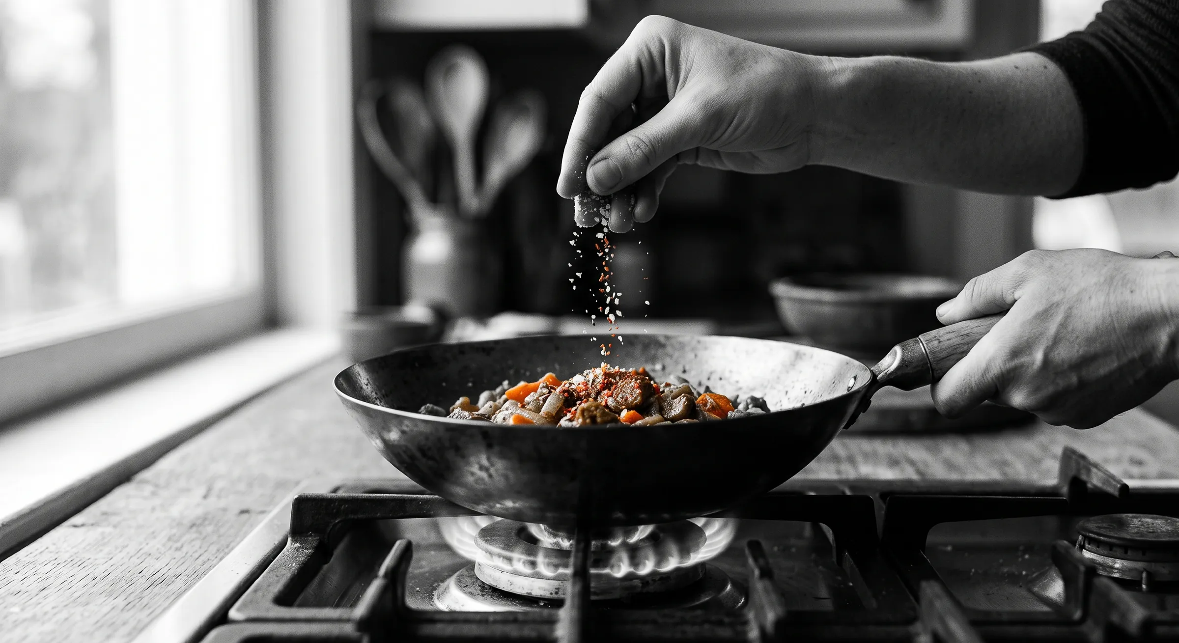 A seasoned hand adding spice to a dish